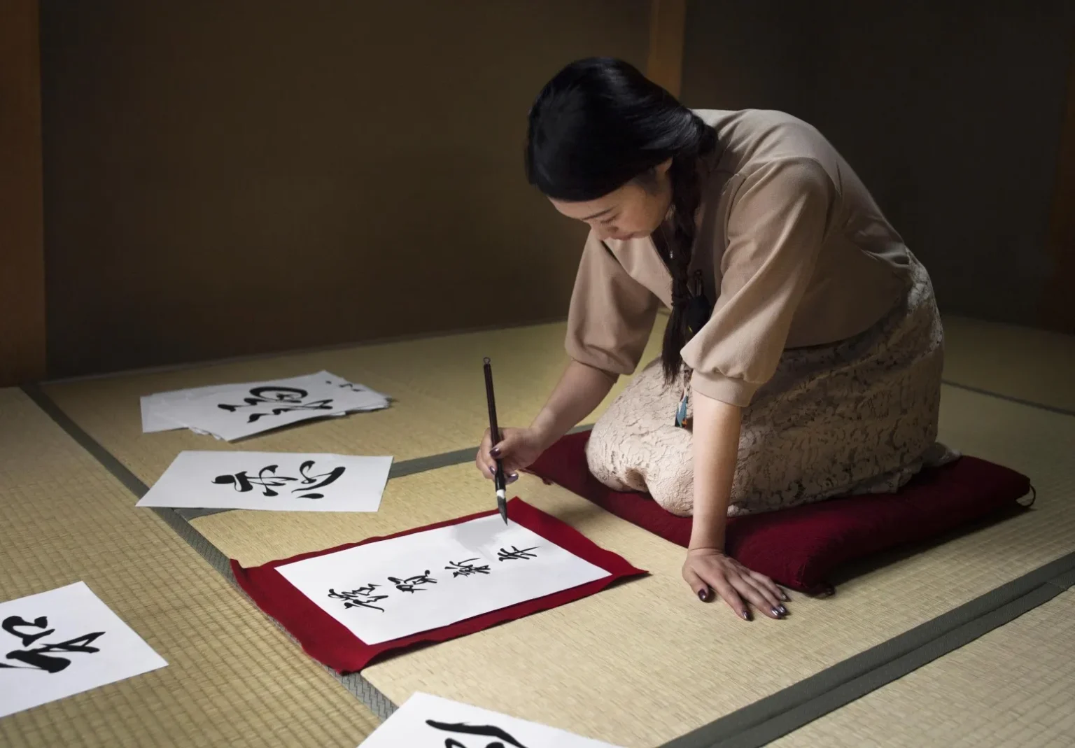 japońskie pismo hiragana: japonka siedzi na ziemi i kaligrafuje znaki