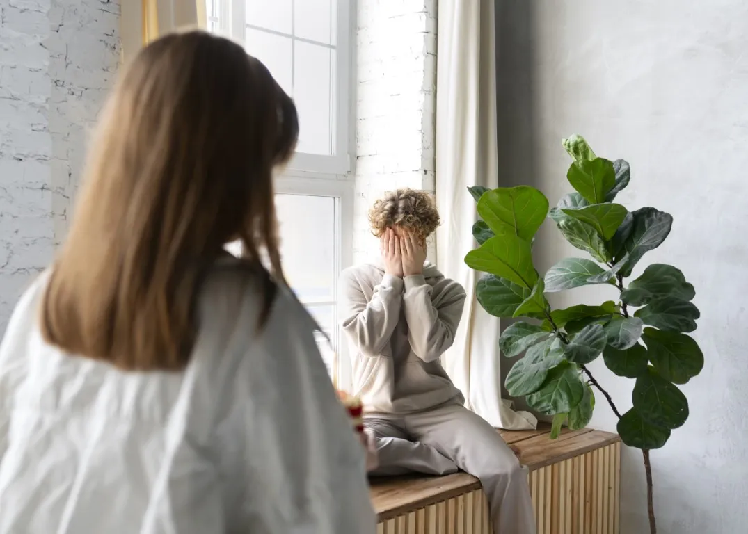 zmęczenie psychiczne: chłopiec chowa twarz w dłoniach z wyczerpania nerwowego