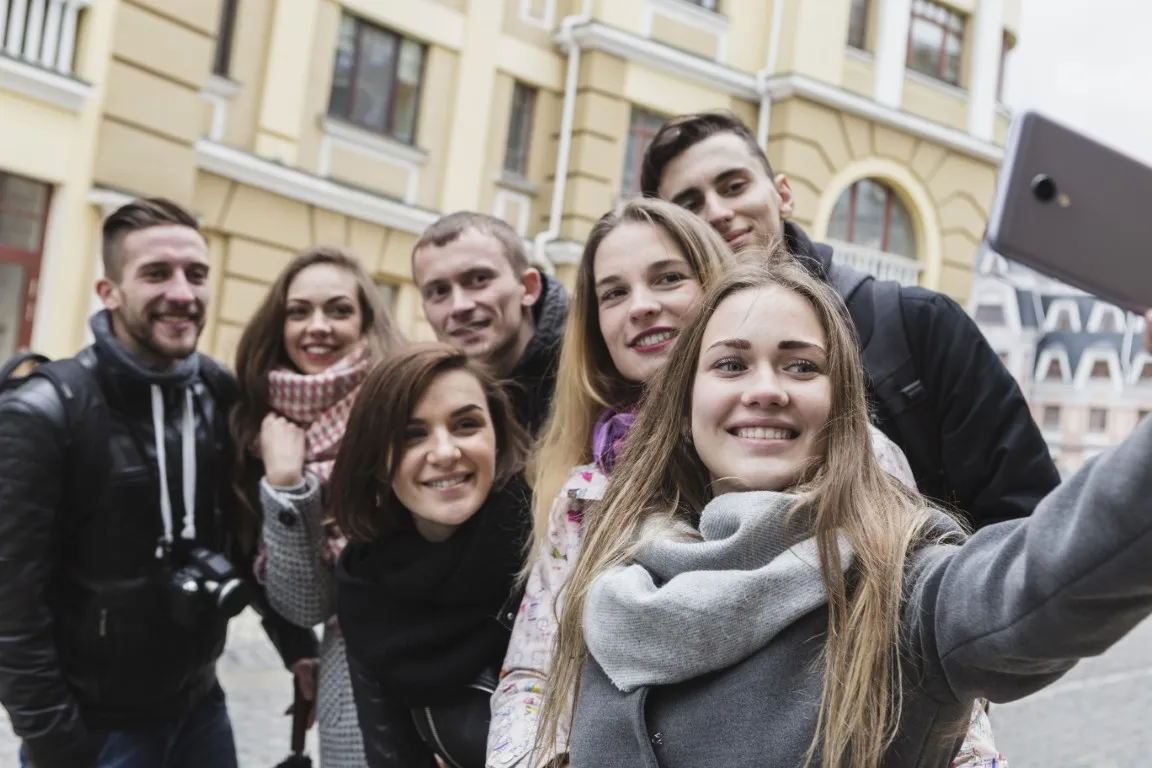 jak uwierzyć w siebie: dziewczyna robi selfie z grupą uśmiechniętych przyjaciół