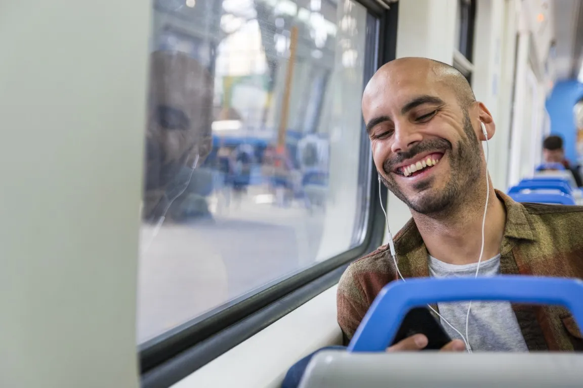 testy na prawo jazdy aplikacja mobilna — mężczyzna w autobusie uczy się teorii na słuchawkach